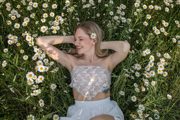 Happy beautiful blonde girl posing in a chamomile field