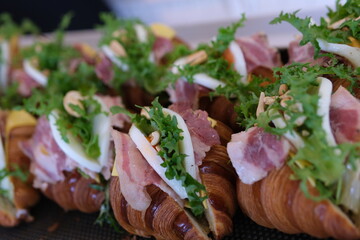 Female hands putting lettuce on a croissant during cooking sandwiches close up. High quality 4k...