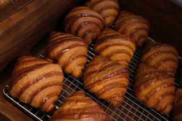 Close-up Croissants Stacked on Wire Rack Cooling Rack. Natural light illuminates the golden brown....