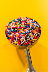 Rainbow Sprinkles in Scoop Against Yellow Background