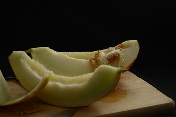 Yellow melon cut in half on black background, copy space