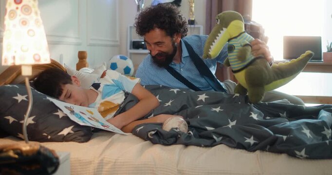 Father playfully wakes his son with a stuffed toy. Businessman wakes his son in the morning. A loving, fun moment as they begin their day. Part 2 of the &ldquo;Dad&rsquo;s Day&rdquo; series.