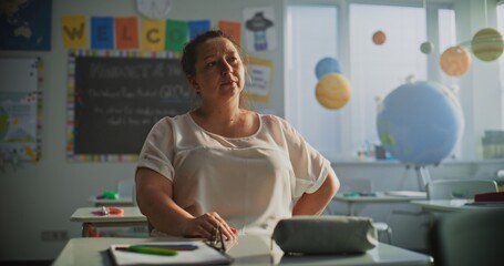 Tired Female Teacher Sitting Alone in Empty Classroom, Relaxing After Class. Woman Feeling Stress,...