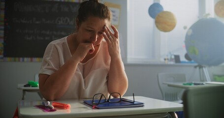 Exhausted Female Teacher Sitting Alone at Desk in Empty Classroom, Having Rest After Lesson and...