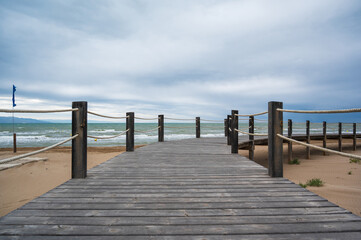 Fototapeta premium Wooden boardwalk leading to the sea on a cloudy day