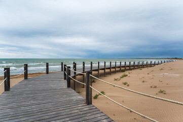 Fototapeta premium Wooden boardwalk leading to the sea on a cloudy day