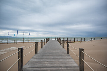 Fototapeta premium Wooden boardwalk leading to the sea on a cloudy day