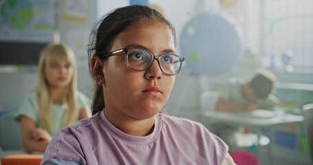 Close Up of Elementary School Girl Sitting at Desk, Raising Hand and Answering Teacher's Question During Geography Lesson. Team of Smart Diverse Kids Studying Environmental Science in Modern Classroom