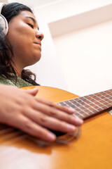Singer songwriter composing new music with acoustic guitar and headphones