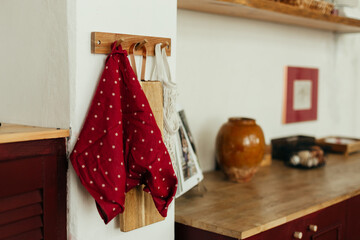 A kitchen scene featuring a wooden cabinet with a checkered orange and white dish towel hanging...