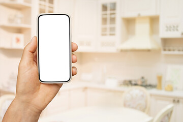 Smart Home Control In Kitchen. Hand holding smartphone with white blank screen.