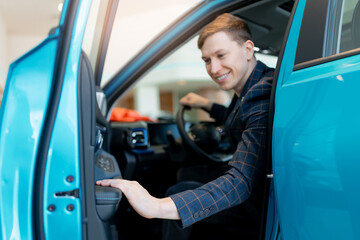 Caucasian young male exploring new car at dealership showroom