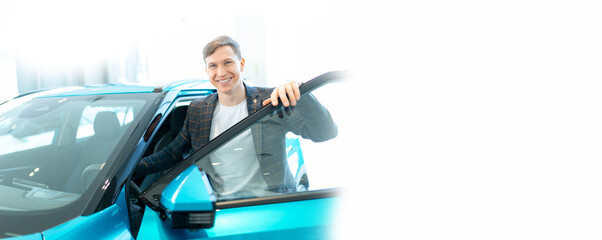 Happy Young man customer just bought new car, banner dealership showroom concept