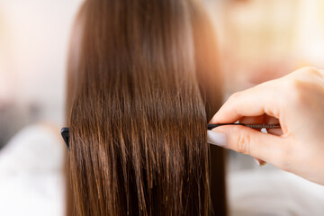 Fototapeta premium Professional haircare styling: caucasian woman with sleek straight hair being combed at salon