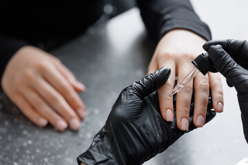Applying oil to nails and cuticles, moisturizing skin after manicure procedure in beauty salon