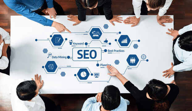 A diverse group of professionals collaborates around a table to develop SEO best practices, data mining strategies, and actionable plans for business growth and success. Amity