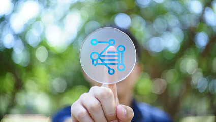 Finger Touching a Transparent Circle Displaying a Network Diagram with a Blurred Green Background of Trees and Foliage in a Natural Setting