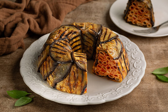 Eggplant Timballo di Melanzane. Grilled eggplants wrap around the pasta and tomato, cheese and baked. Italian meal. Brown table surface.