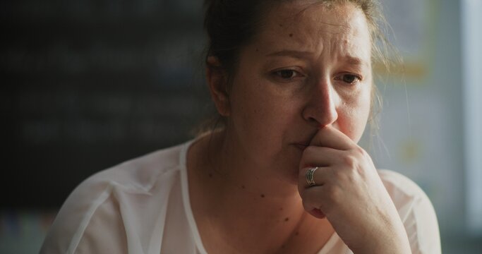 Exhausted Female Tutor Taking Off Glasses, Sitting Alone in Empty Classroom, Having Rest After Lesson. Teacher Feeling Stress, Burnout and Emotional Struggle, Working in Primary School. Close Up Shot. - Powered by Adobe