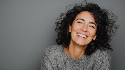 portrait of mature woman laughing against grey background successful middle aged woman in casual with toothy smile looking at camera cheerful happy beautiful latin lady smiling with copy space no log