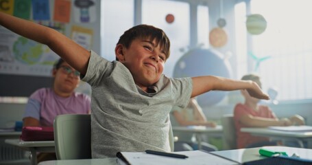 Primary School Boy Sitting at Desk, Raising Hand and Giving Correct Answer on Teacher's Question...