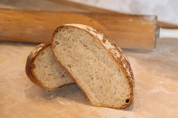 Country Bread Round Loaf of Rustic White Bread with Sliced Half isolated on wooden Background closeup side view of italian Baked items