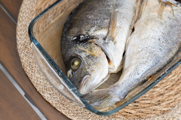 Freshly prepared Dorado fish displayed in a transparent glass baking dish