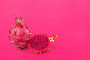 Fresh whole and sliced red fleshed dragon fruit Isolated on vibrant pink background