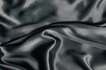 Silky black fabric draped elegantly on a flat surface in soft lighting