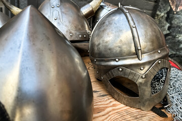 Detailed metal helmets displayed on a wooden surface in a historical reenactment setting