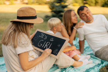A family enjoys a picnic with a baby gender reveal outdoors on a sunny day