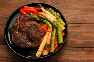 Savory grilled steak served with vibrant roasted vegetables on a wooden table