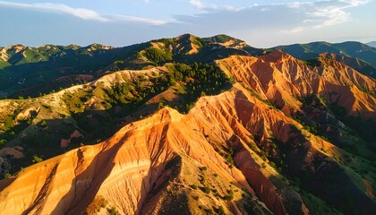 Fototapeta premium Aerial View of Rolling Hills with Red Rock Formations and Scattered Green Trees