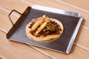 Traditional beef steak taco with potatoes, nopal, and onion, street food