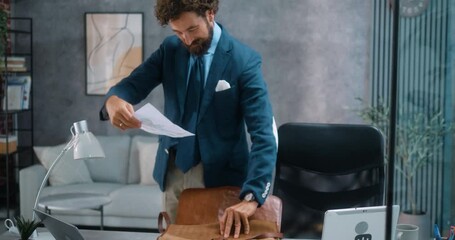 Businessman father packs up after work, gently placing his child's drawing in his bag before leaving the office for home. Part 43 of the “Dad’s Day” series. - Powered by Adobe