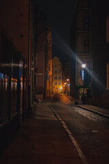 Dimly Lit Cobblestone Street at Night in Gdansk with Historic Facades