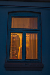 Close Up of Blue Wooden Window with Warm Interior Light in Belarus