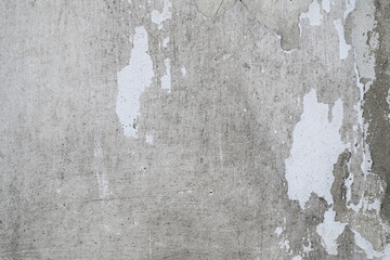 Rough texture of old concrete or plastered wall with fragments of peeling white paint. Ideal for...