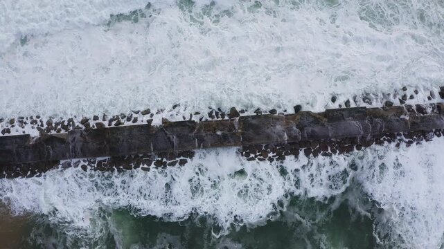 Huge waves crashing over Breakwater during winter storm Atlantic waves washing the lighthouse on Praia da Aguda sandy beach at Aguda settlement near Porto, Portugal. TOP view 4K flying drone video.