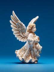 Ceramic angel figurine isolated on blue background, photograph