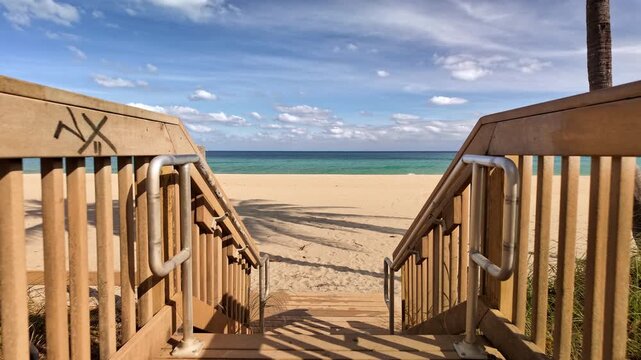Wooden boardwalk entrance surrounded by lush greenery leading to a tropical island beach with white sand and clear blue water