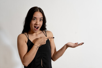 Surprised young woman showing and pointing to empty hand on white background