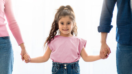Family Care. Cute Little Preschool Girl Holding Hands With Parents, Looking At Camera And Smiling,...