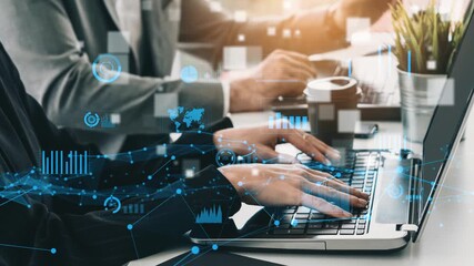 Business professionals focus on data analysis using laptops, with digital graphs and charts overlaying the workspace, symbolizing teamwork and modern technology in action. Xenic - Powered by Adobe