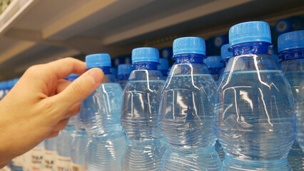 Many sparkling water bottles standing in a row and a male hand taking one