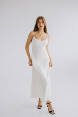 Fashion model posing in white dress and black high heels