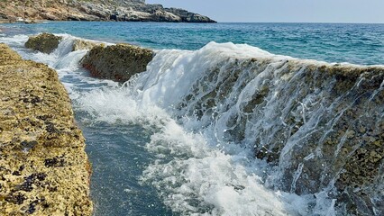 Small waves gently splash through natural stone slabs on Kory Beach in Alanya, Turkey. Peaceful seaside view perfect for travel, relaxation, and nature themes