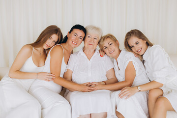 Family of five women showing love and connection embracing on sofa