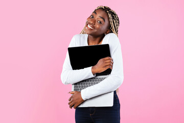 Technology Lover Concept. Happy black woman hugging laptop with black blank empty screen, holding...