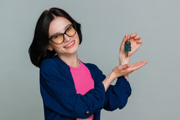 Woman real estate agent lifting hand showing the keys of new home house apartment, buying or...